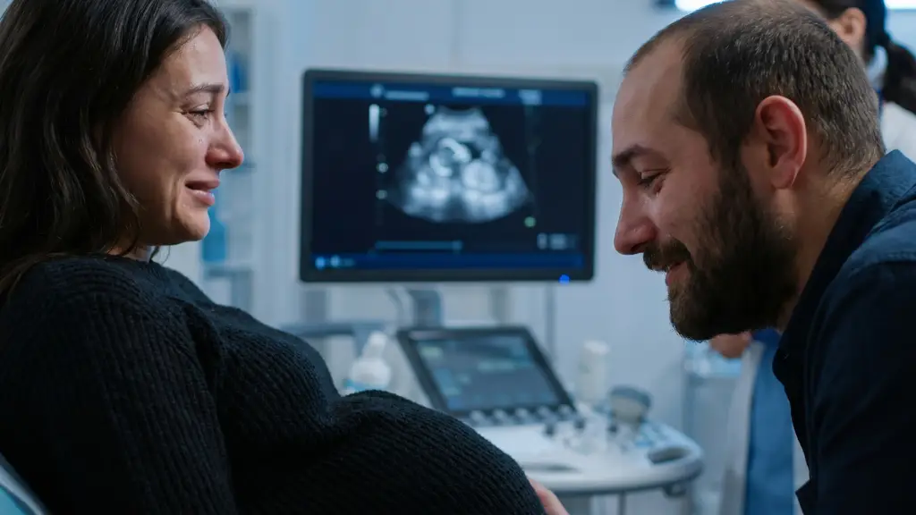Pareja mirando con emocion la pantalla del monitor durante la primera ecografia de confirmacion en el primer trimestre de gestacion