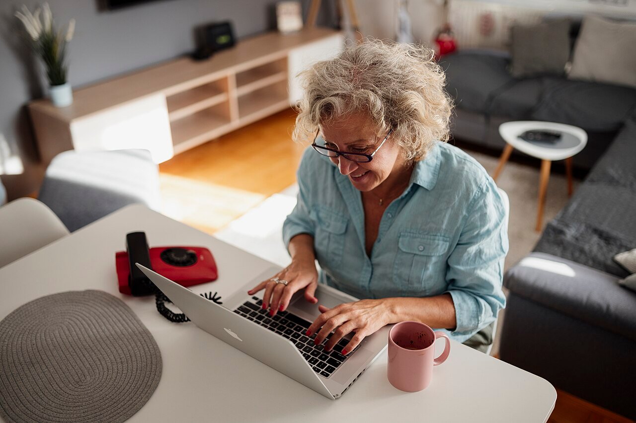Mujer mayor trabajando con un portátil desde casa durante la jubilación flexible