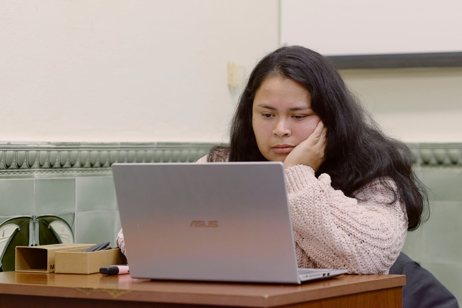 Estudiante revisando documentación académica junto a un portátil