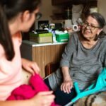 Persona mayor conversando con una cuidadora en casa, imagen sobre la reforma de dependencia y discapacidad de 2026