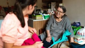 Persona mayor conversando con una cuidadora en casa, imagen sobre la reforma de dependencia y discapacidad de 2026